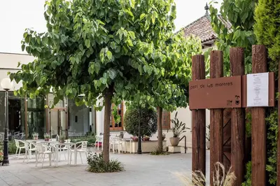 a sign in a courtyard with a tree and tables at Balneari Termes Victòria in Caldes de Montbui