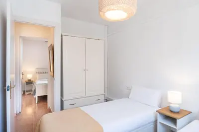 a white bedroom with a bed and a table at Cozy Apt with charm and exquisite natural light in Barcelona