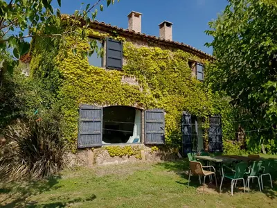 a building covered in ivy with a table and chairs at Masia Vilatersana in Sant Llorenc Savall