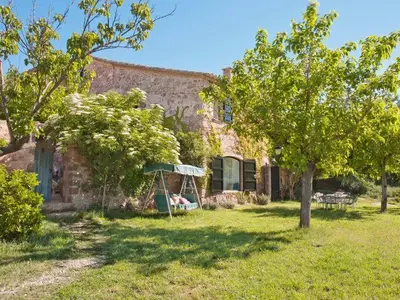 a stone house with a swing in the yard at Masia Vilatersana in Sant Llorenc Savall