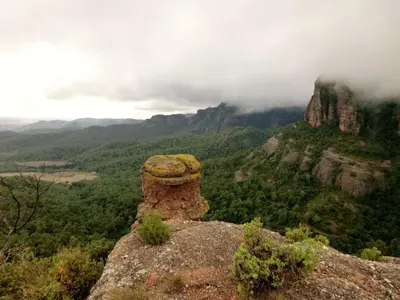 a view of a mountain with clouds and trees at Masia Vilatersana in Sant Llorenc Savall
