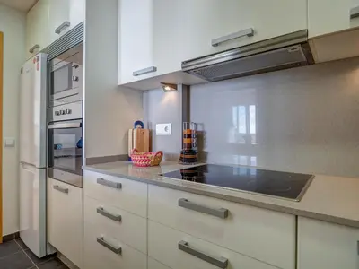 a kitchen with white cabinets and a stove at Ocean Skyline Penthouse by Hello Homes Sitges in Sitges