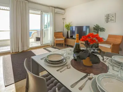 a living room with a table with plates and flowers at Ocean Skyline Penthouse by Hello Homes Sitges in Sitges