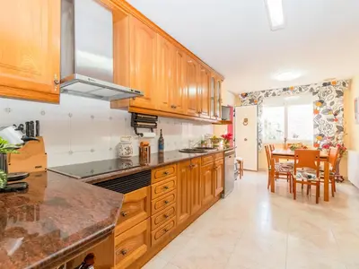 a kitchen with wooden cabinets and a table with chairs at Holiday Home Aurea by Interhome in Pineda de Mar