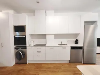 a kitchen with white cabinets and a stainless steel refrigerator at Mazi Apartments Loft in Mataró