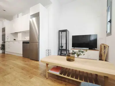 a living room with a tv and a wooden table at Mazi Apartments Loft in Mataró