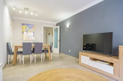 a dining room and living room with a table and a tv at HomeHolidaysRentals Liberty - Costa Barcelona in Pineda de Mar