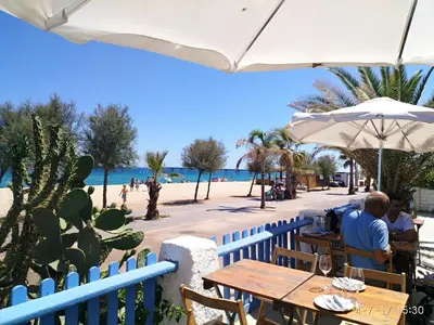 two people sitting at a table near the beach at Hostal Estudios in Badalona