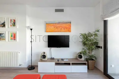a living room with a tv on a white wall at Sitges PORT - Con piscina, a 5 minutos de la playa in Sitges