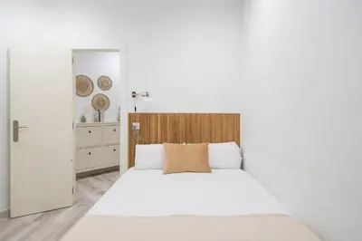 a bedroom with a white bed with a wooden headboard at Apartment Next to Sagrada Familia, the Essence of Barcelona in Barcelona