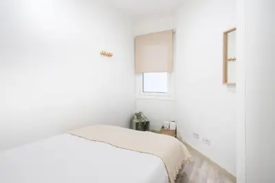 a white bedroom with a bed and a window at Apartment Next to Sagrada Familia, the Essence of Barcelona in Barcelona