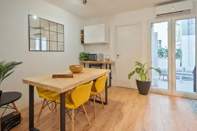 a kitchen and dining room with a wooden table and yellow chairs at BCN: ¡Exclusivos y cerca del Camp Nou! in El Arrabal