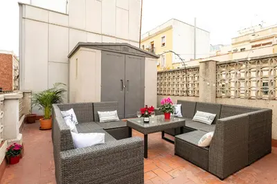 a patio with wicker chairs and tables on a balcony at Barcelona Beach Home in Barcelona