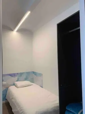 a white room with a bed and a light at L'Havana Xica in Vilanova i la Geltrú