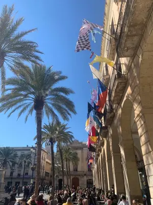 a crowd of people standing in front of a building with flags at L'Havana Xica in Vilanova i la Geltrú
