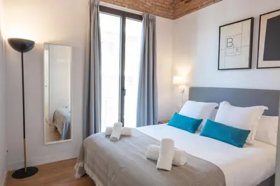a bedroom with a large bed with blue and white pillows at Feelathome Stadium Apartments in Hospitalet de Llobregat