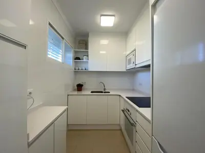 a white kitchen with white cabinets and a sink at Montaber Apartments - Sant Pol de Mar in San Pol de Mar