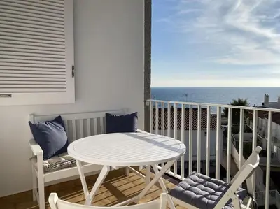 a white table and chairs on a balcony with the ocean at Montaber Apartments - Sant Pol de Mar in San Pol de Mar