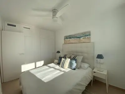 a white bedroom with a large white bed with pillows at Montaber Apartments - Sant Pol de Mar in San Pol de Mar