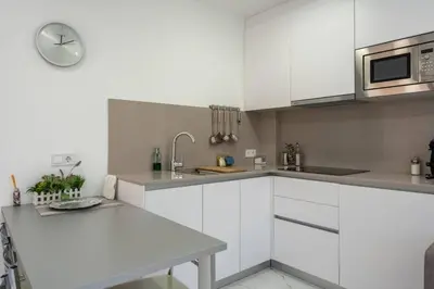 a white kitchen with white cabinets and a sink at Apartamentos Rosa de Abril in Teià