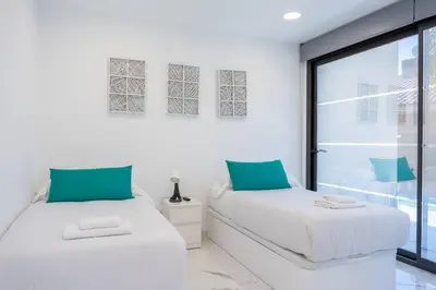 two beds in a white room with a window at Apartamentos Rosa de Abril in Teià