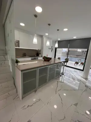a kitchen with white walls and marble floors and a counter at Apartamentos Rosa de Abril in Teià