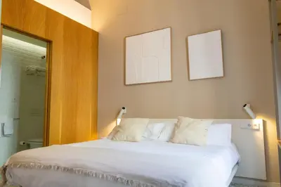 a bedroom with a white bed with two pictures on the wall at 