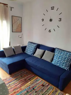 a blue couch in a living room with a clock on the wall at Pisito bonito y funcional en Pineda De Mar in Pineda de Mar