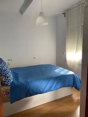 a bed in a white room with a blue blanket at Pisito bonito y funcional en Pineda De Mar in Pineda de Mar