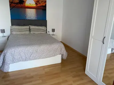 a white bedroom with a bed and a wooden floor at Pisito bonito y funcional en Pineda De Mar in Pineda de Mar