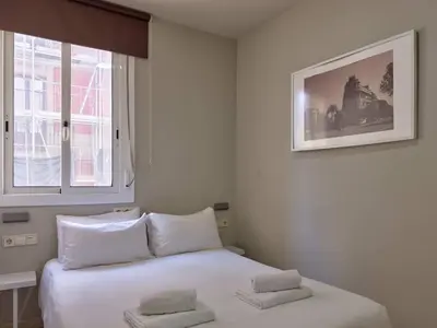 a bedroom with a bed with white sheets and a window at Stay U-nique Apartments Torre Damians in Barcelona
