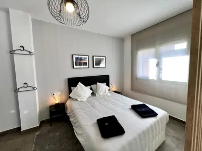 a white bedroom with a large bed with two black objects on it at Loft moderno en buena ubicación in Terrassa