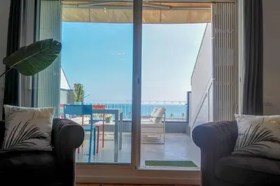 a living room with two chairs and a large glass door at The Moonlight Sea View by Hello Homes Sitges in Sitges