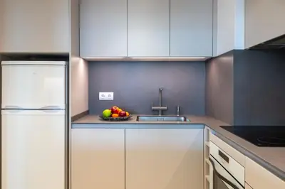 a kitchen with white cabinets and a bowl of fruit at Sitges ARENA - dos piscinas frente al mar in Sitges