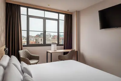 a hotel room with a bed and a window at Petit Palace Eixample in Barcelona