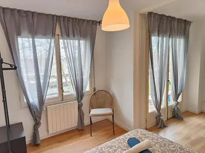 a bedroom with two windows and a chair and a bed at Cute apartment Sant Adria beach in Sant Adria de Besos