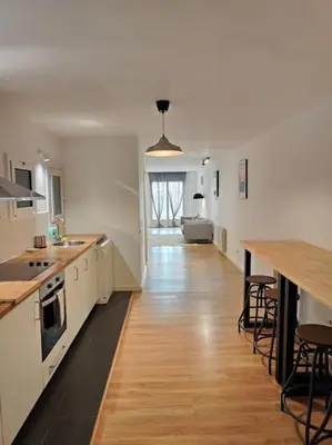a large white kitchen with a long wooden floor at Cute apartment Sant Adria beach in Sant Adria de Besos