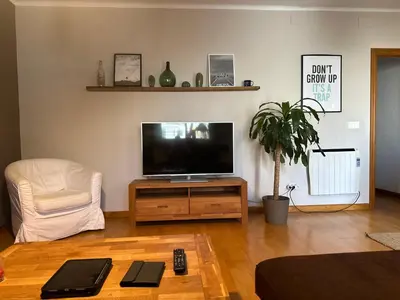 a living room with a flat screen tv and a chair at MODERNO APARTAMENTO EN EL CENTRO in Vilanova i la Geltrú