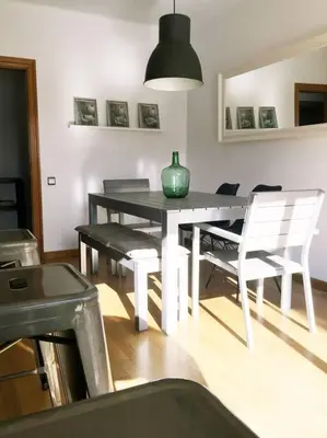 a dining room table with chairs and a green vase on it at MODERNO APARTAMENTO EN EL CENTRO in Vilanova i la Geltrú