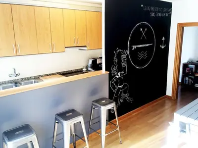 a kitchen with two stools and a chalkboard on the wall at MODERNO APARTAMENTO EN EL CENTRO in Vilanova i la Geltrú