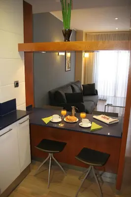 a kitchen with a counter with two stools and a table at Apartaments Independencia in Barcelona
