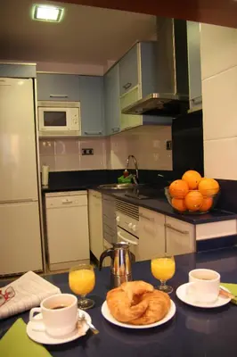 a kitchen with a table with bread and two glasses of orange juice at Apartaments Independencia in Barcelona