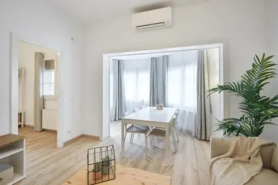 a white living room with a table and a plant at BBarcelona Calabria Flat in Barcelona