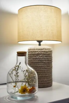a glass vase with flowers in it next to a lamp at BBarcelona Calabria Flat in Barcelona