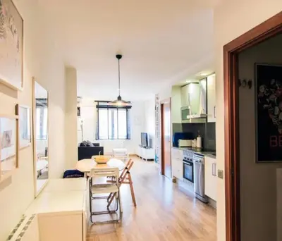 a kitchen and living room with a table and chairs at SWEET BCN Plaza Universidad in Barcelona