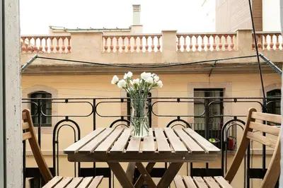 a wooden table with a vase of flowers on a balcony at Lodging Apartments Barceloneta Mar in Barcelona