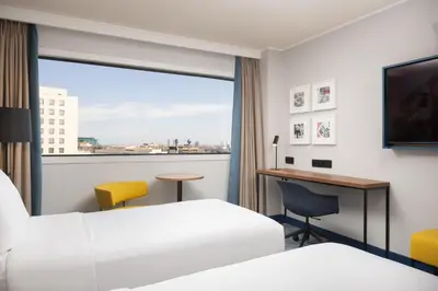 a hotel room with two beds and a desk and a window at Hilton Barcelona in Barcelona