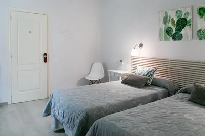 a bedroom with two beds and a table with a chair at Blanc Guest House in Barcelona