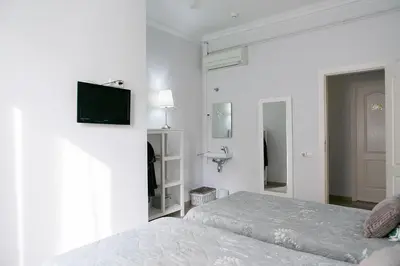 a white bedroom with a bed and a tv on the wall at Blanc Guest House in Barcelona