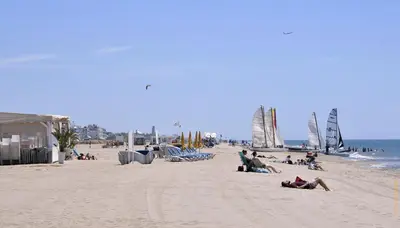 a group of people sitting on a beach with sailboats at Ciudad de Castelldefels in Castelldefels